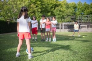 Group of kids playing soccer in a lush green park on a sunny day.